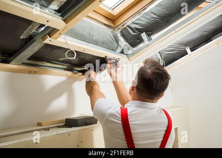 l'appaltatore sta installando un pannello di legno sotto il tetto Foto Stock