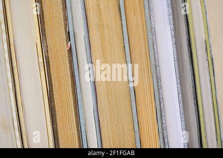 Libri antichi disposti in una riga in libreria antiquaria, dettaglio closeup su pagine gialle colorate da lato Foto Stock