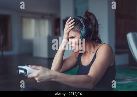 Giovane giocatore sconvolto donna con cuffia fare un errore quando si gioca online, facepalm Foto Stock