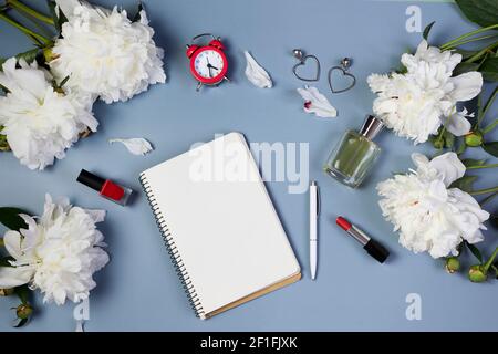 apri il notebook per scrivere piani, per fare lista o sogni con peonie fresche, sveglia, su sfondo azzurro Foto Stock