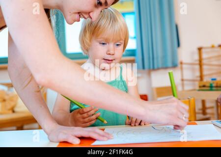 I bambini di Disegno con matite a giocare a scuola Foto Stock