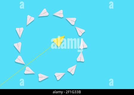 Un aeroplano di carta giallo vola attraverso un cerchio di piani bianchi. Sfondo blu. Era piatto. Il concetto di creatività e successo. Foto Stock