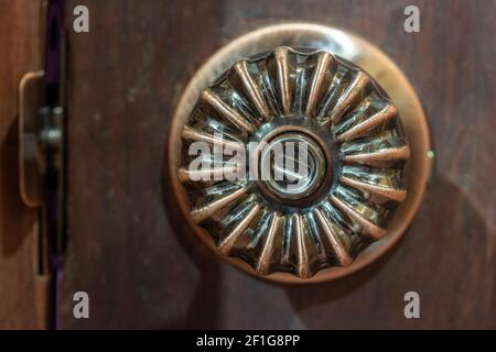 Close up old decorative door knob on wood door. Detail of a aged round ball door knob on brown door. Stock Photo