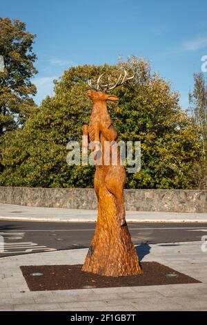 Scultura creativa di uno stag rosso che si addentra nell'aria, scolpito interamente da un albero esistente su Mission Road a Killarney, County Kerry, Irlanda Foto Stock