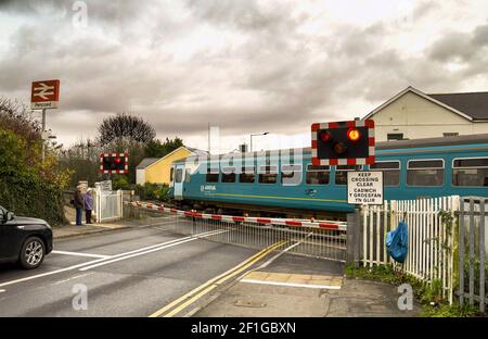 Pencoed, Galles - Dicembre 2017: Un treno diesel attraversa una strada a Pencoed sulla linea principale. Le barriere di sicurezza sono abbassate e le luci rosse mostrano. Foto Stock