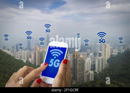 5G o LTE presentazione. Donna mano utilizza lo smartphone con la città moderna sullo sfondo Foto Stock