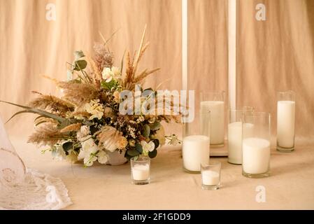 Decorazioni da fiori secchi belli in vaso bianco su fondo di tessuto beige. Decorazione della camera Foto Stock