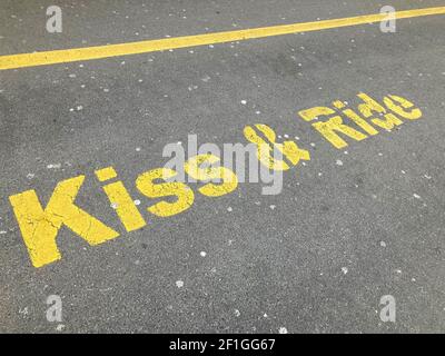 Iscrizione gialla Kiss and Ride dipinta su asfalto presso la stazione di sosta di Zug, Svizzera Foto Stock