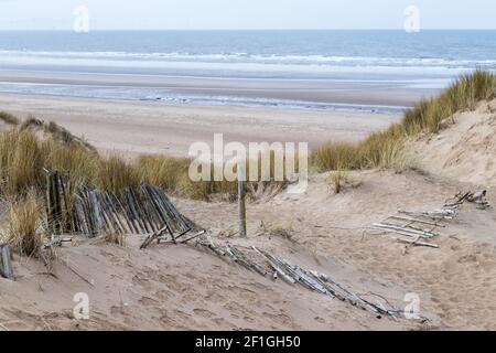 Una recinzione di rickety soffiata sopra dal vento e la relativa età vista che conduce giù alla spiaggia a Formby vicino a Liverpool. Foto Stock