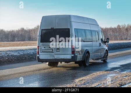 il minibus va sulla strada invernale sporca Foto Stock