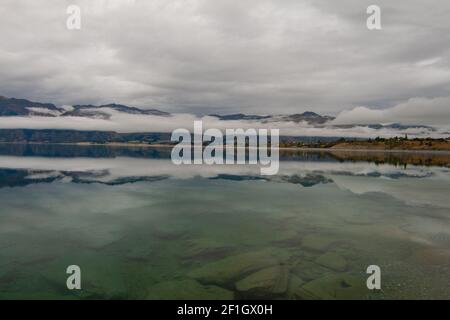 Lago Hawea vicino a Wanaka, Isola del Sud della Nuova Zelanda. Melancolico nuvoloso e nebbia paesaggio mattutino. Foto Stock