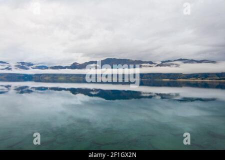 Lago Hawea vicino a Wanaka, Isola del Sud della Nuova Zelanda. Melancolico nuvoloso e nebbia paesaggio mattutino. Foto Stock