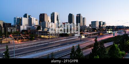 Il traffico di prima mattina passa davanti agli edifici che riflettono Sunrise Light a Bellevue, Washington Foto Stock