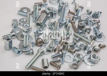 Chromeplated bulloni e dadi su sfondo bianco Foto Stock