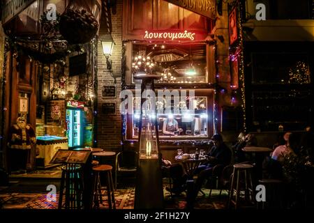 01-03-2018 Atene Grecia all'interno di un bar scuro a Natale con cliente al telefono e riscaldamento fuoco e server dietro bancone Foto Stock