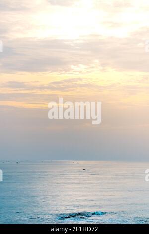 Una vista affascinante dell'oceano calmo che brulica sotto tramonto nel cielo nuvoloso Foto Stock