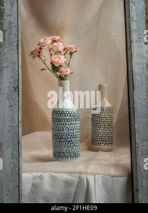 Bouquet di fiori rosa in vasi di ceramica blu fatti a mano con struttura in legno su tela da tavolo testurizzata Blush. Decorazione domestica, spazio di copia, fuoco selettivo. Foto Stock