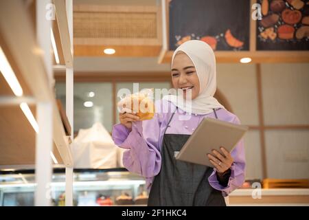 proprietario musulmano di affari che controlla il suo prodotto sul display dentro il negozio Foto Stock