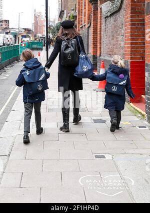 Londra, Gran Bretagna. 8 Marzo 2021. Una donna invia i suoi figli a una scuola elementare nel centro di Londra, in Gran Bretagna, l'8 marzo 2021. In mezzo a un senso misto di nervosismo ed eccitazione, milioni di bambini sono ritornati nelle scuole attraverso l'Inghilterra lunedì sotto la fase uno della 'roadmap' del governo britannico alla ripresa dalla pandemia di COVID-19. Credit: Han Yan/Xinhua/Alamy Live News Foto Stock