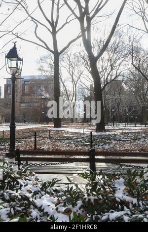 USA, New York City, NY - panca vuota nel Washington Square Park coperto di neve in inverno guardando verso la Freedom Tower, o One World Trade Center Foto Stock