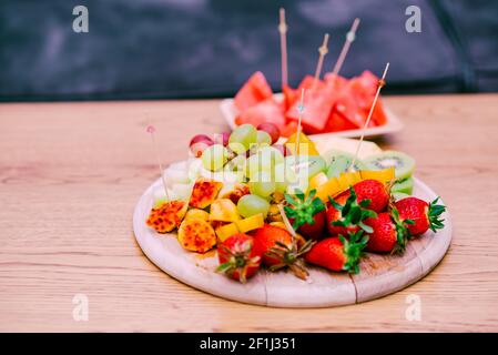 Frutta fresca su tavola di legno. Piatto di frutta organico crudo con berrii, meloni, kiwi, mango, ananas, Anguria, Prickly Pear, Carambola, fragola. Foto Stock