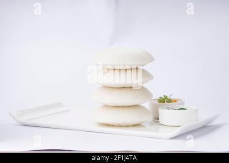 Folle o Idli, l'articolo principale della colazione dell'india del sud che è disposto splendidamente sulla base rettangolare bianca con due piccole ciotole di sambar e chutney sul wh Foto Stock