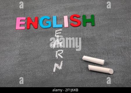 Impara l'inglese. Lettere colorate dell'alfabeto su una tavola di gesso scuro. Foto Stock