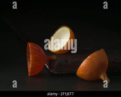 Composizione artistica con metà di buccia di cipolla. Vista ravvicinata. Tasto basso, sfondo scuro. Modello con buccia di cipolle su sfondo nero. Foto Stock