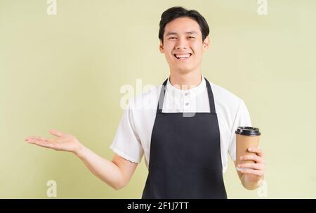 Cameriere asiatico che tiene la tazza di carta e sorridente Foto Stock