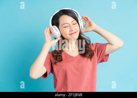 Bella donna asiatica che indossa cuffie senza fili bianche e il telefono di tenuta in mano mentre balla alla musica Foto Stock