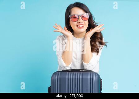 Bella donna asiatica seduta in posa accanto a valigia e di preparazione per viaggi Foto Stock