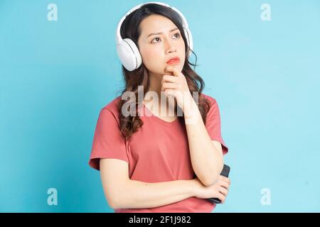 Bella donna asiatica che indossa cuffie wireless bianche con una premurosa faccia Foto Stock