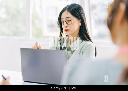 Donna d'affari asiatica che prende appunti durante l'incontro Foto Stock