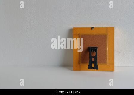Rivestire il lato opposto della cornice fotografica appoggiandosi al cemento parete su tavolo di legno Foto Stock
