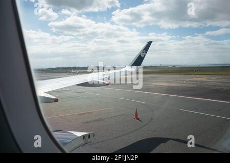 Un volo Air New Zealand al terminal nazionale di Auckland con porta di carico aperta. Immagine scattata all'interno dell'aereo seduto sul sedile del finestrino. Foto Stock