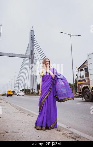 Giovane donna europea con capelli corti in viola tradizionale saree. Ritratto esterno in luce solare tenue. India, Bangalore Foto Stock