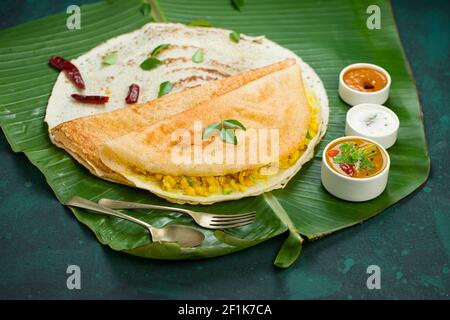 DOSA  Masala dosa, famoso prodotto per la colazione dell'India del sud che viene preparato in padella di ferro di casta in modo tradizionale e disposto sopra una foglia di banana fresca, con scuro Foto Stock