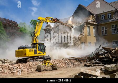 Cantiere digger giallo casa demolente per la ricostruzione Foto Stock