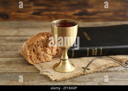 Calice di vino con Sacra Bibbia e pane su legno sfondo Foto Stock