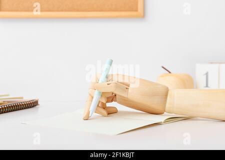 Mano di legno con penna e taccuino sul tavolo, primo piano Foto Stock
