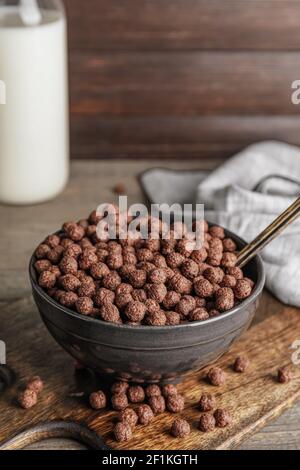 Ciotola con gustose palle di mais al cioccolato su sfondo di legno Foto Stock