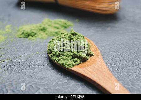 Cucchiaio con tè matcha in polvere su sfondo scuro Foto Stock