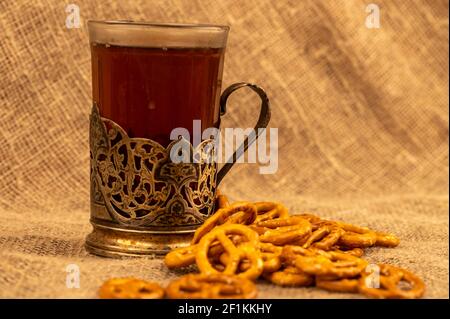 Grissini salati e pretzel salati sfusi e un bicchiere di tè in un portabicchieri sul tavolo. Messa a fuoco selettiva in primo piano. Foto Stock