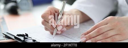 Dottore che compila l'anamnesi medica dei pazienti in primo piano d'ufficio Foto Stock