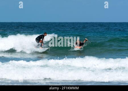 Surfer che taglia un altro surfer che cattura un'onda nel Oceano Atlantico sulla costa della Bretagna in Foto Stock