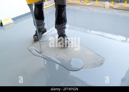 L'addetto alla costruzione rinnova il pavimento del balcone e versa la resina impermeabile e. incollare prima di scheggiare e. Foto Stock