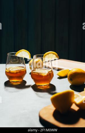 primo piano di un bicchiere con un cocktail alcolico in un bicchiere con limone su sfondo grigio Foto Stock