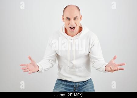 Ritratto di arrabbiato furioso uomo maturo in bianco felpa con cappuccio gridando alla telecamera Foto Stock