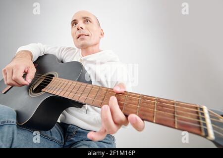 Bald uomo di mezza età che si diverti a suonare la chitarra e a firmare una canzone Foto Stock