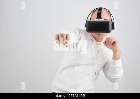 Ritratto di un uomo di mezza età in realtà virtuale che combatte in videogioco, isolato su bianco Foto Stock